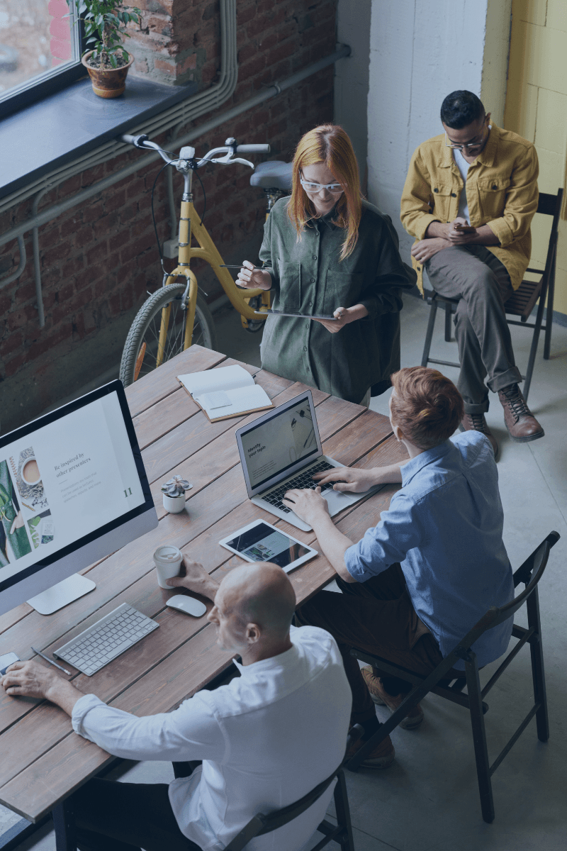 Team in a meeting about IT Service Desk software around a table with laptops