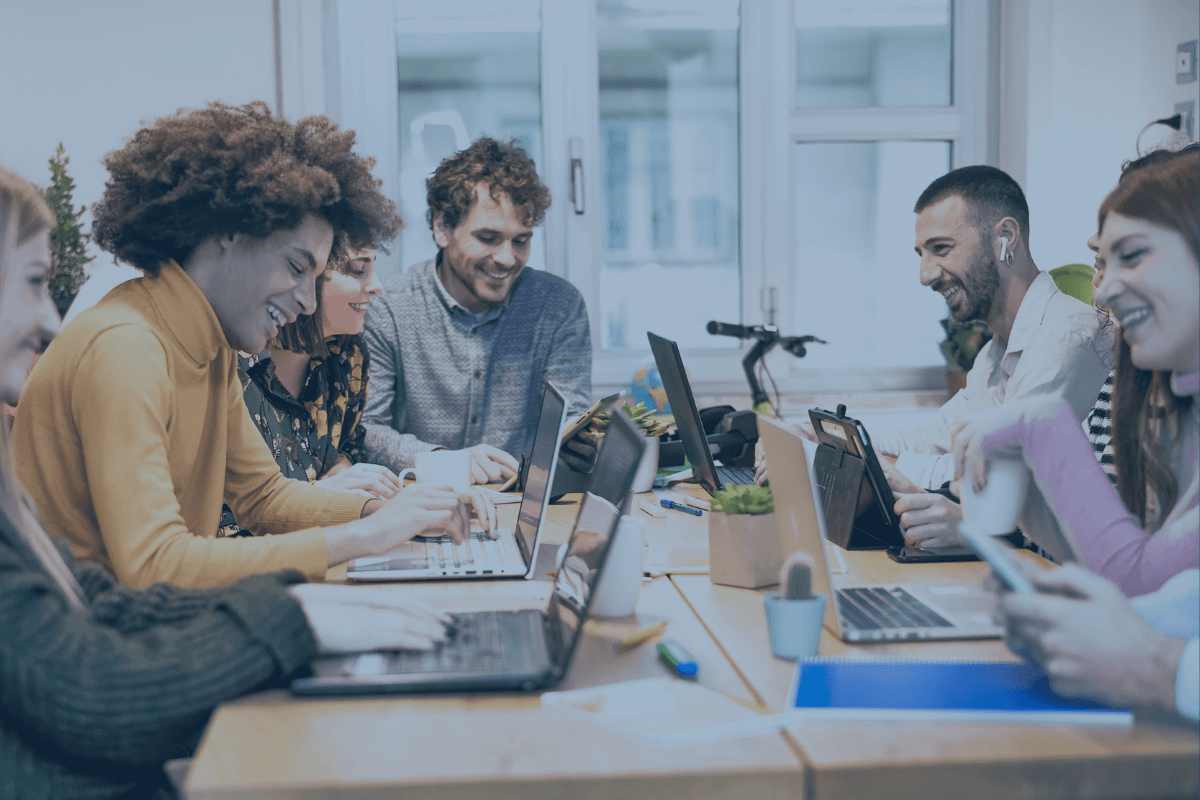Team meeting about incident and change management around a table with laptops. Mojo Helpdesk enables IT teams to deliver IT helpdesk services in an organized fashion.